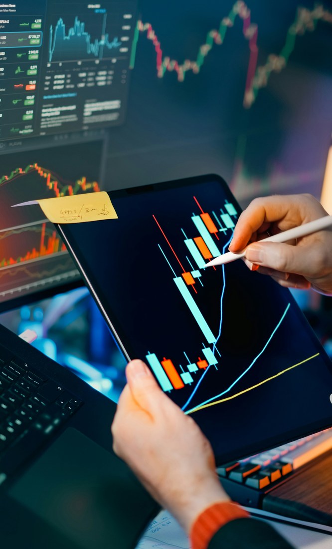 Hands drawing trend lines on a candlestick chart during a trading session